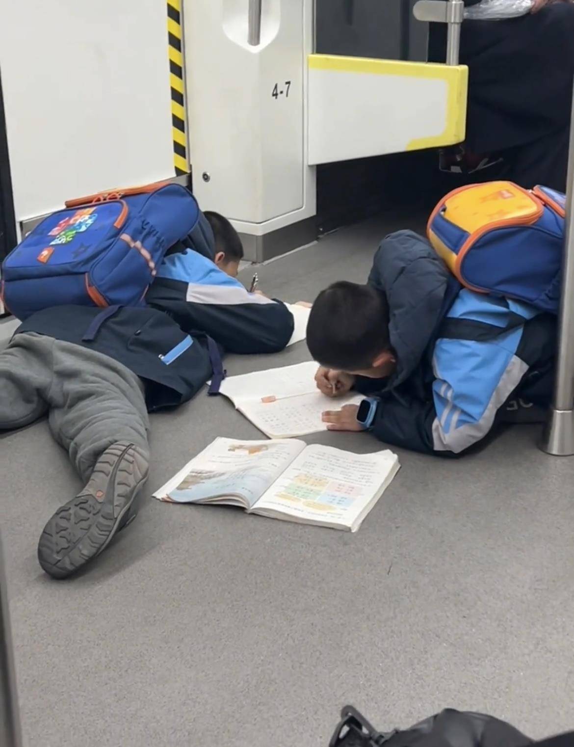 两名小孩哥一上地铁就滑铲倒地，趴地上写作业，引来数万网友共鸣：这才是童年的样子